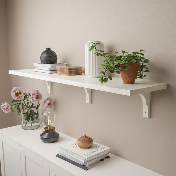 Wandplank met decoratieve artikelen: planten, boeken, vazen en bloemen.