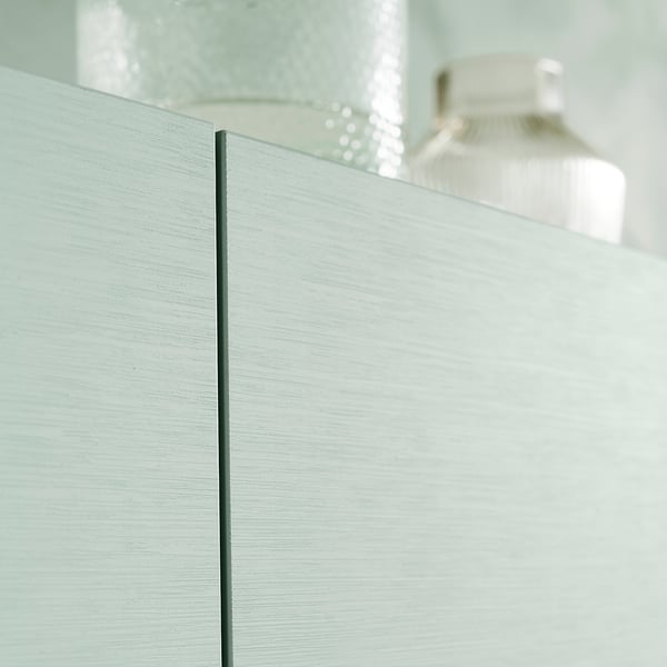 Witte BESTÅ wandkast met getextureerde glazen deur en strak zwart scharnier.