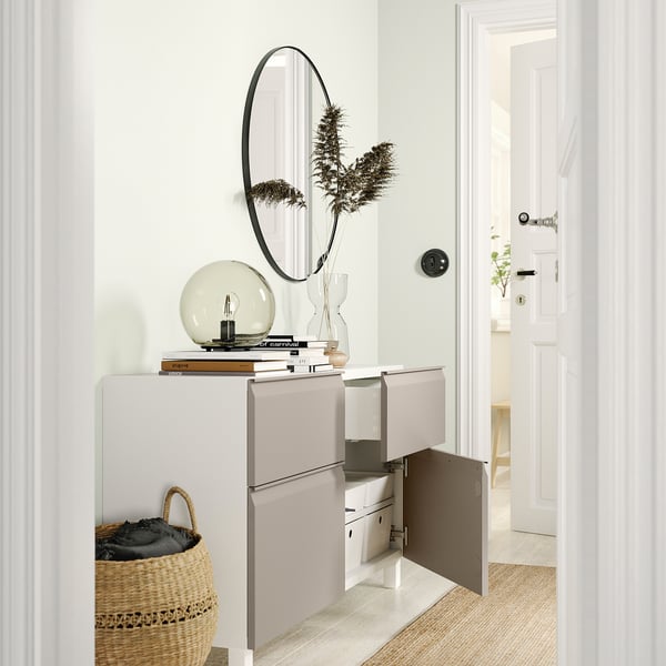 Modern wit BESTÅ dressoir met open deuren die opbergvakken en planken onthullen, bedekt met decoratieve voorwerpen.