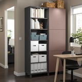 Moderne kantoorhoek met BESTÅ zwart opbergmeubel, houten tafel en stoel. Planken bevatten boeken en dozen. Dichtbij raam met rolluiken.