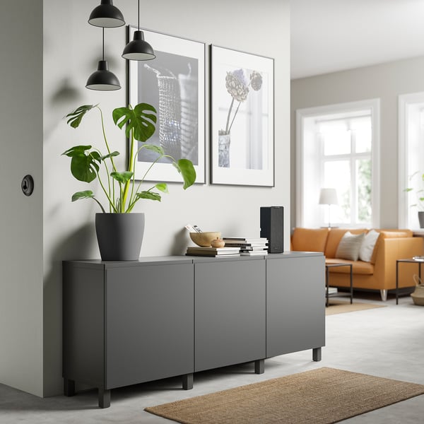 Moderne woonkamer met grijze BESTÅ kast, plant, lampen, kunst, oranje bank.