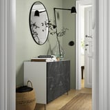 Moderne hal met BESTÅ dressoir, marmeren blad, spiegel, boeken, vaas en mand.