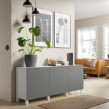 Moderne woonkamer met BESTÅ dressoir, planten, lampen, foto en gezellige zitplaatsen.