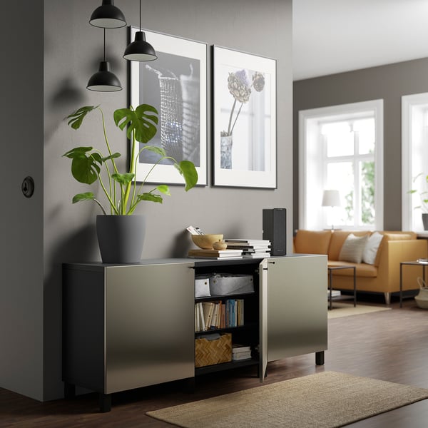 Moderne woonkamer met donkergrijs BESTÅ dressoir, verstelbare planken, boeken, plant, soft-close deuren, kunst en verlichting.