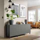 Grijs BESTÅ dressoir in de woonkamer, moderne, verstelbare planken, met plant, kunst en geluidssysteem.