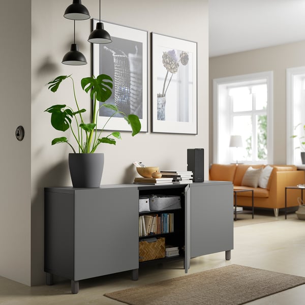 Moderne woonkamer met BESTÅ opslag, open deur met boeken en inrichting, twee foto's, plant.