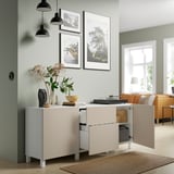Moderne woonkamer met BESTÅ dressoir, inrichting, lampen, natuurfoto's, oranje bank en groot raam.