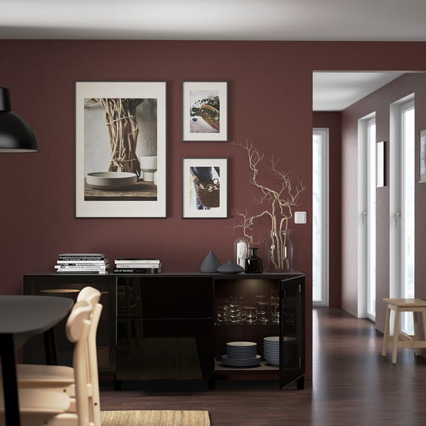 Moderne eetkamer met donkerrode muren, zwart dressoir en inrichting.