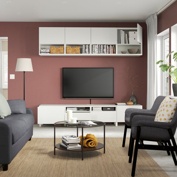 Moderne woonkamer met rode muren, grijze bank, tv op witte standaard met planken en wandkast.