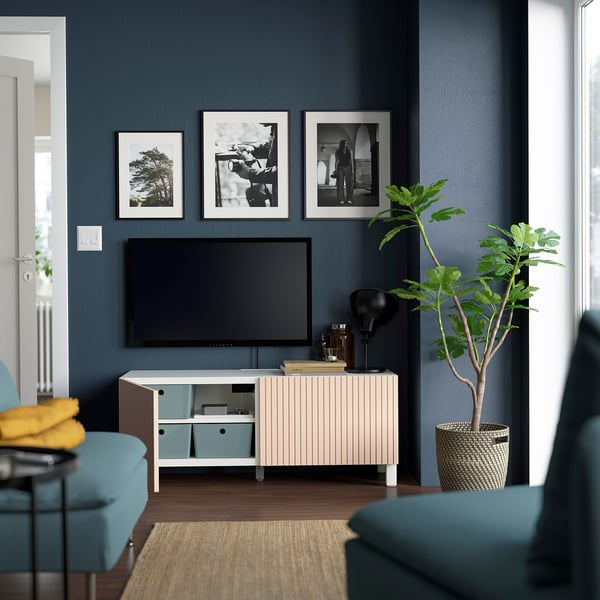 Moderne woonkamer: BESTÅ tv-meubel, berkenhouten deuren, blauwe muren, fauteuils, plant.