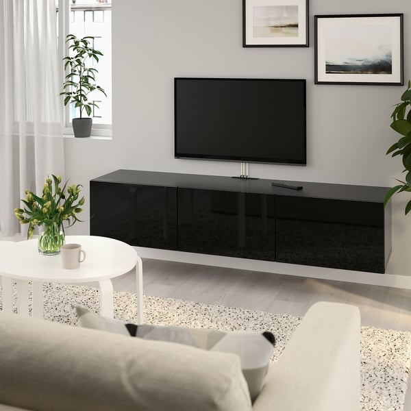 Moderne woonkamer met groot zwart BESTÅ tv-meubel. Het is smal en herbergt een flatscreen-tv. Witte bank en salontafel op de voorgrond.