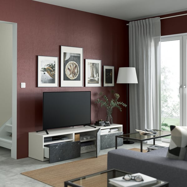 Moderne woonkamer met kastanjebruin BESTÅ tv-meubel, flatscreen, verstelbare poten en natuurlijk licht uit het raam met gordijnen. Kunst en lamp decor.