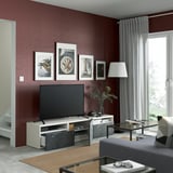 Moderne woonkamer met kastanjebruin BESTÅ tv-meubel, flatscreen, verstelbare poten en natuurlijk licht uit het raam met gordijnen. Kunst en lamp decor.