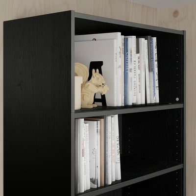 Zwarte BILLY boekenkast met boeken en decor. Hoge, donkere houten planken bevatten boeken van verschillende formaten en bieden veelzijdige opbergruimte.
