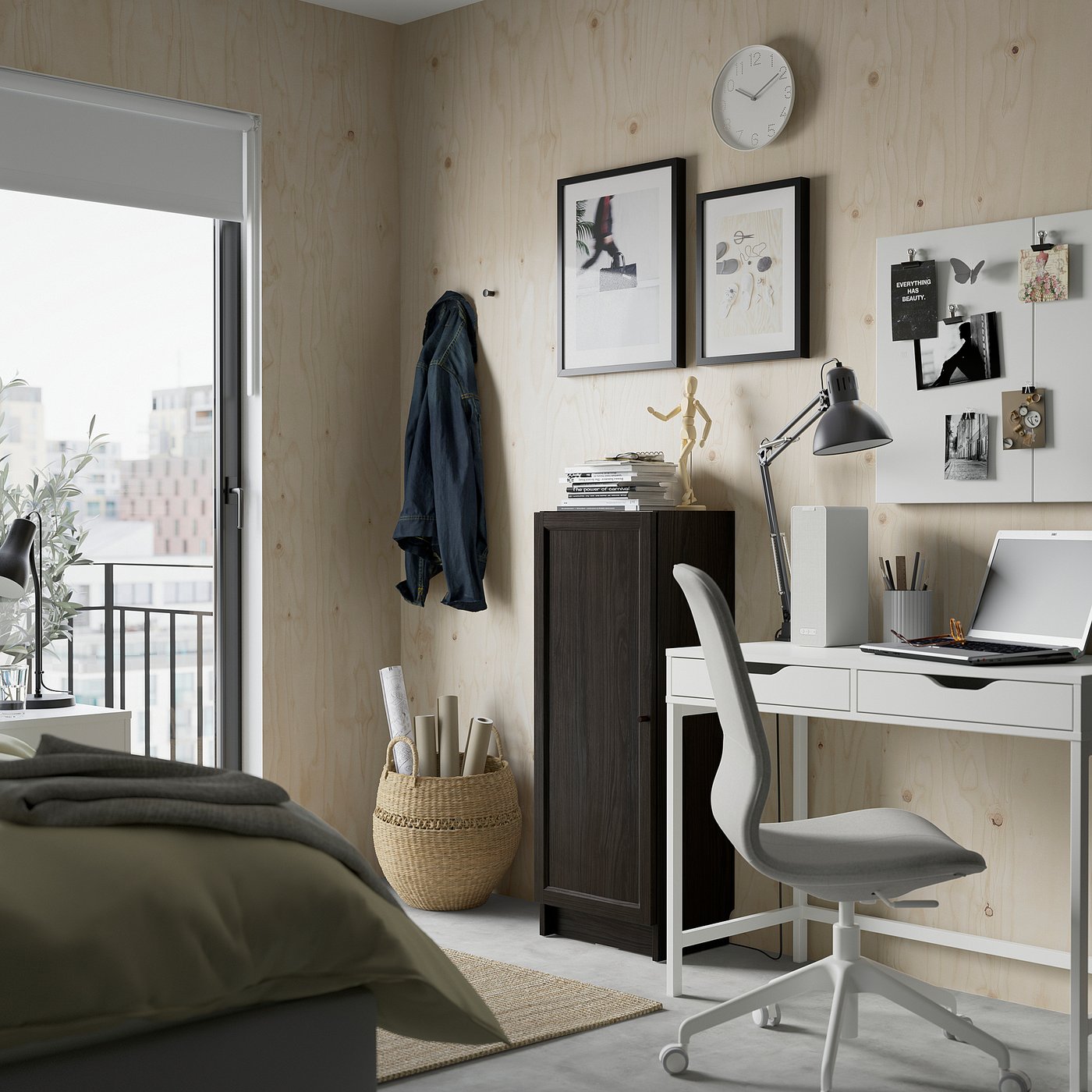 Moderne slaapkamer met BILLY boekenkast, stoel en bureau. Uitzicht op de stad vanuit het raam, artistieke prints en een georganiseerd bureau met benodigdheden.