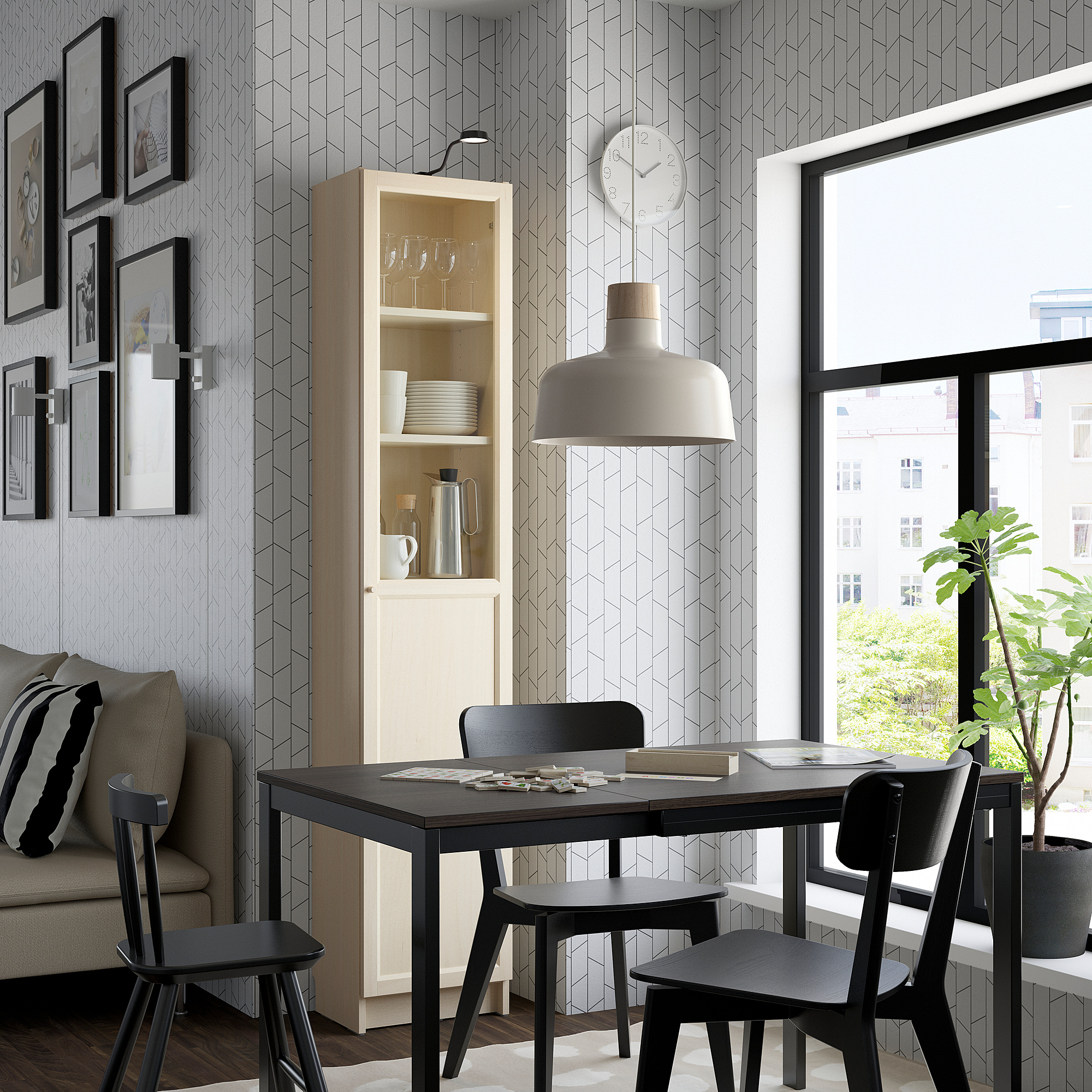Moderne eethoek met zwarte tafel, stoelen, een hoge lichtgekleurde BILLY boekenkast met een glazen deur en een groot raam.
