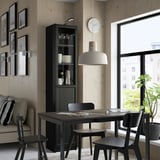 Minimalistische eetruimte met BILLY boekenkast, donkerhouten tafel, stoelen, klok en planten.