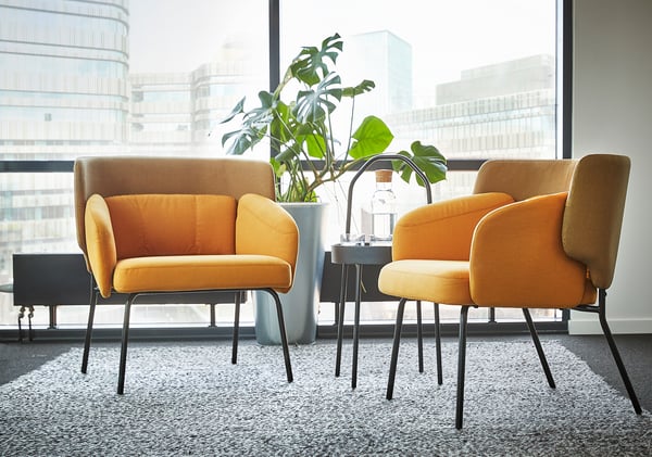 Modern interieur met twee fel oranje BINGSTA fauteuils, grote fabriek en uitzicht op de stad.