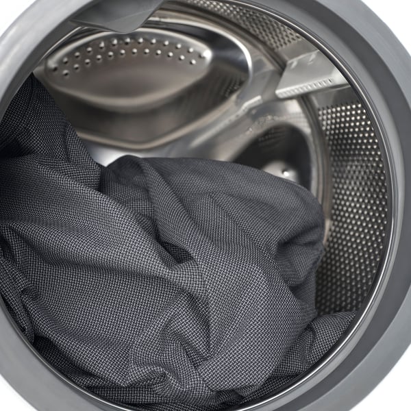 Wasmachinetrommel met donkere kleding, met machinewasbare stofverzorging.