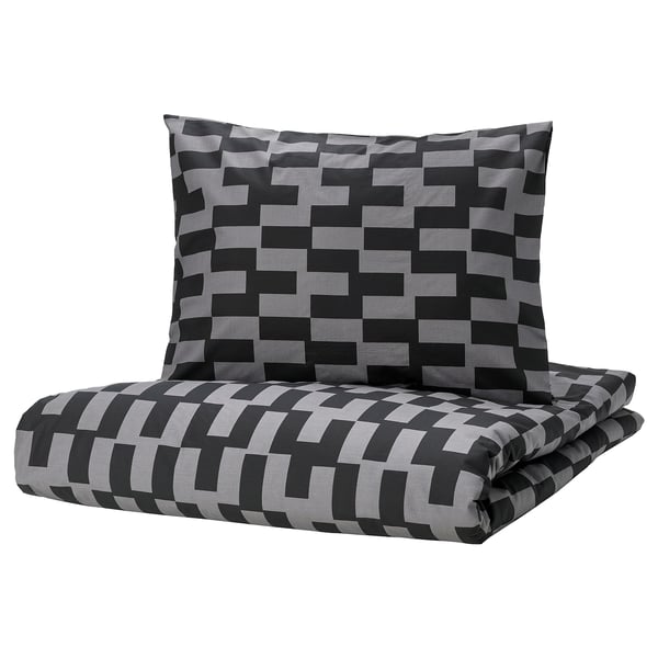 Zwart en grijs geometrisch patroon beddengoed set, gevouwen met kussen.