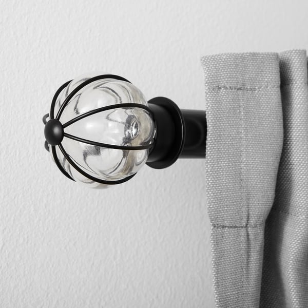 Glas en metalen gordijn eindstuk gemonteerd op de muur, met lichtgrijs gordijn.