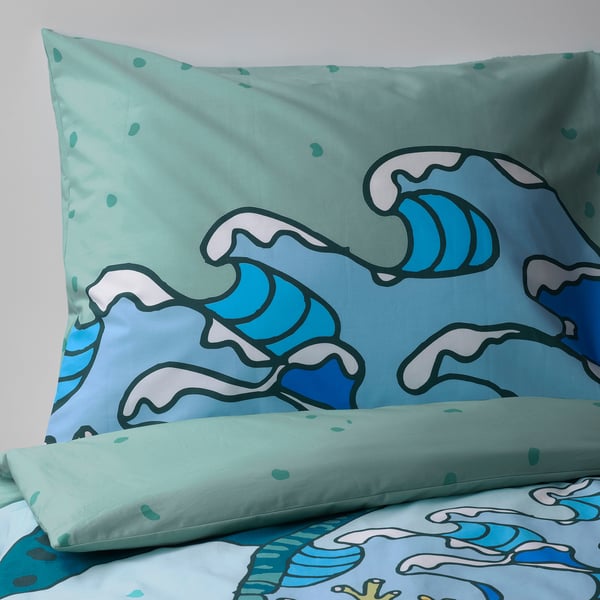 Twee kussens met levendige patronen met turquoise en blauwe golfmotieven op een mint achtergrond.