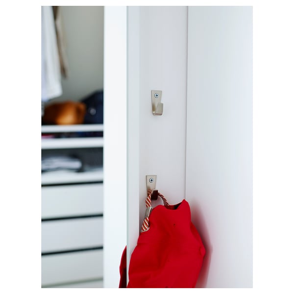 Twee zinken haken met nikkel afwerking, verticaal gemonteerd aan de muur, met rode zak.