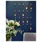 Wanddisplay met meerdere blauwe handdoekhaken en rode labels. Witte bloemen in vaas.