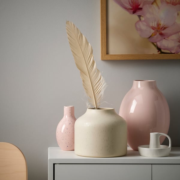 Kleine BLODBJÖRK roze gespikkelde keramische vaas, met een grote gevederde pluim, neergestreken op een witte plank met twee andere vazen, een grote en een kleine.