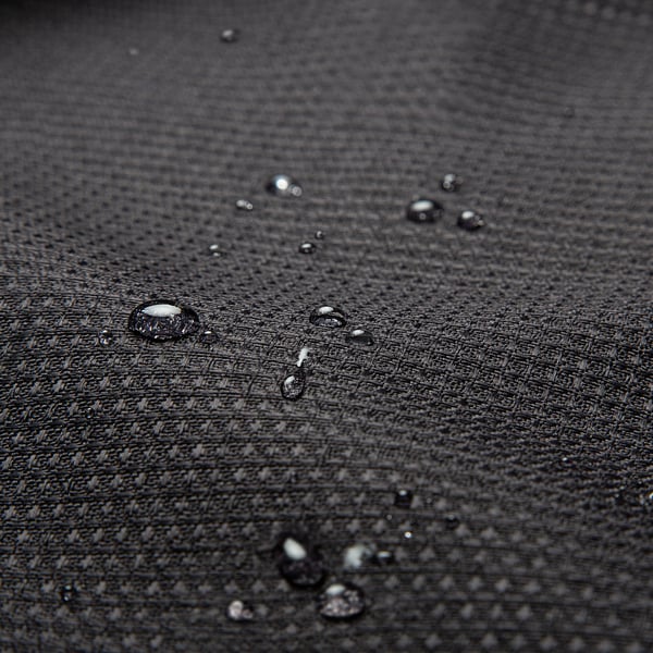 Close-up van waterdruppels die parelen op getextureerde, waterafstotende stof, die de waterafstotende eigenschap laat zien.