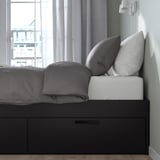 Modern bedframe met lades en kussens, met strak design en opbergruimte.