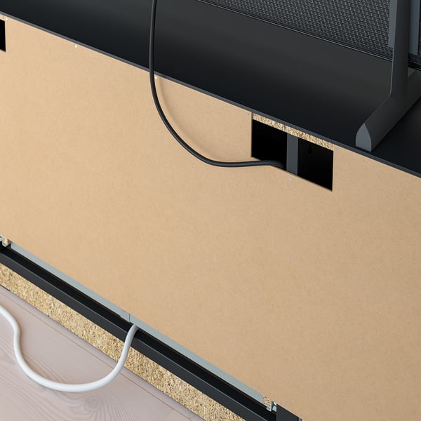 Zwart tv-meubel met kurken onderstel, voorzien van kabelmanagement en ventilatie, geplaatst tegen een lichtgekleurde muur.