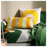 Gele en witte gestreepte kussens, ananaskussen op groen bed. Levendige pop in gezellige slaapkamer.