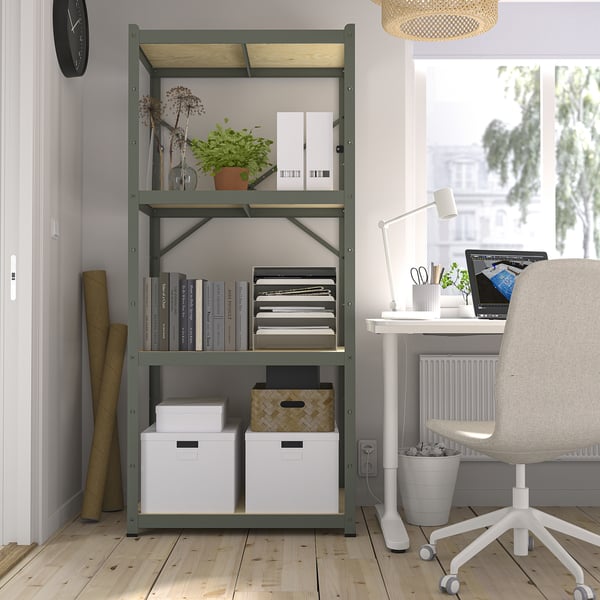 Thuiskantoor met BROR groene metalen plank met boeken, dossiers en planten. Bureau met laptop, stoel en witte vloerlamp. Klok aan de muur.