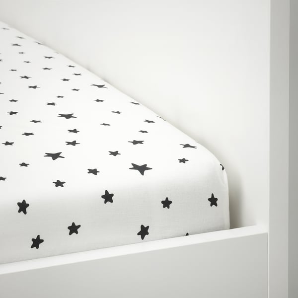 Zwart hoeslaken met stermotief op een witte matras, vastgezet met elastische randen.