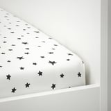 Zwart hoeslaken met stermotief op een witte matras, vastgezet met elastische randen.
