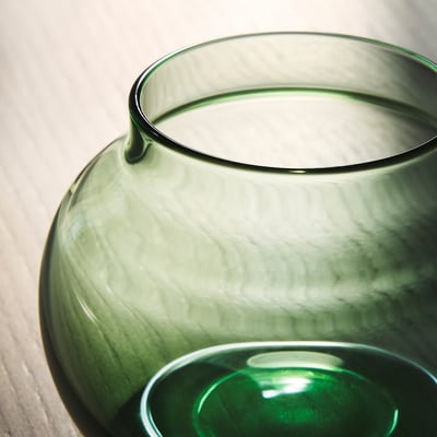 Drie kleurrijke glazen vazen in roze, geel en groen, elk met een unieke vorm, op een rij gerangschikt.