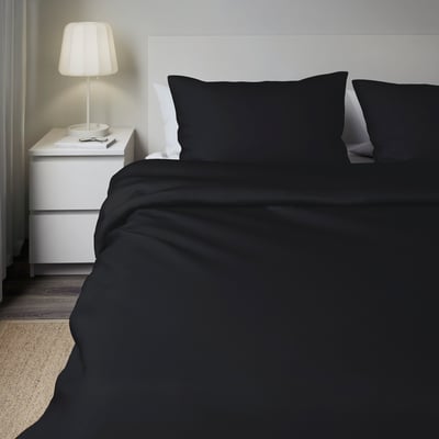 Moderne slaapkamer met DVALA donkergrijs beddengoed op een eenpersoonsbed, met een strak design en een eenpersoons nachtkastje met een lamp.