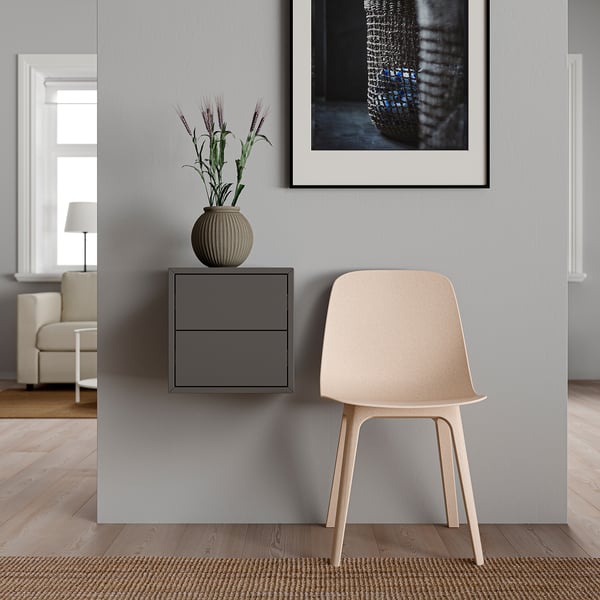 Minimalistische hoek met witte stoel, grijze EKET kast, plant en ingelijste kunst.