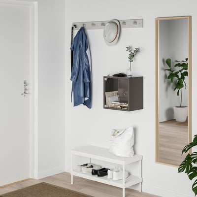 Kleine witte EKET kubusplank hangt aan de muur en bewaart tijdschriften onder een blauwe jas.