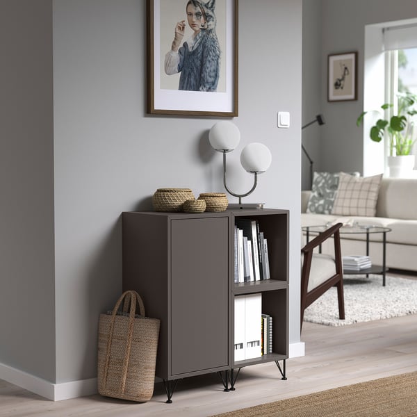 EKET bijzetkast houdt manden, boeken en lampen vast, naast een bank in een minimalistische woonkamer.