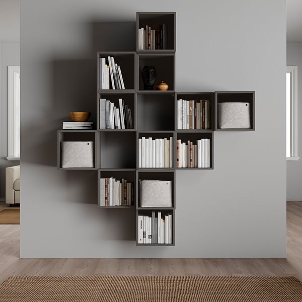 Moderne aan de muur gemonteerde grijze boekenplank, gevuld met boeken en decoratieve artikelen. Asymmetrisch ontwerp met meerdere compartimenten.