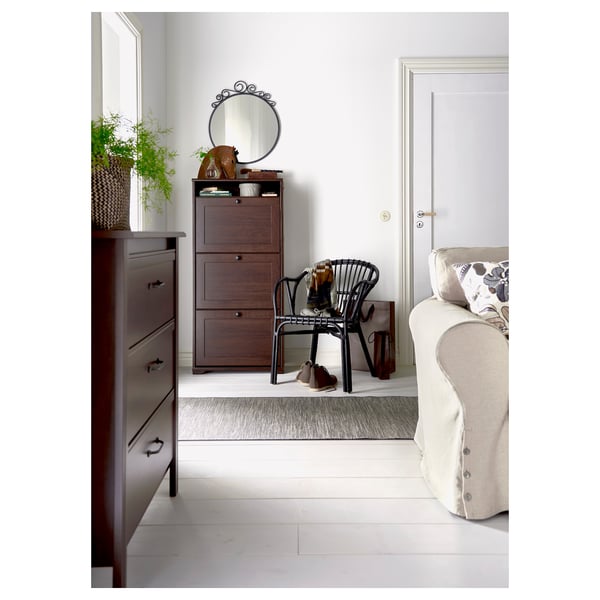 Decoratieve kamer met EKNE spiegel, donkerhouten kast, witbeige bank, zwarte stoel en plantendecoraties.