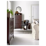 Decoratieve kamer met EKNE spiegel, donkerhouten kast, witbeige bank, zwarte stoel en plantendecoraties.