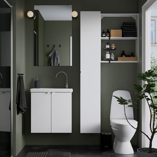 Moderne badkamer: witte ENHET berging, spiegel, wastafel, toilet. Donkergroene muren. Witte kast is klein maar ruim.