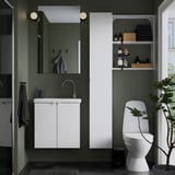 Moderne badkamer: witte ENHET berging, spiegel, wastafel, toilet. Donkergroene muren. Witte kast is klein maar ruim.