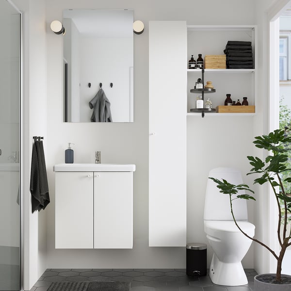 Moderne witte badkamer met zwarte accenten. Drijvende ijdelheid, spiegel, toilet en plant. Planken tonen handdoeken en toiletartikelen.