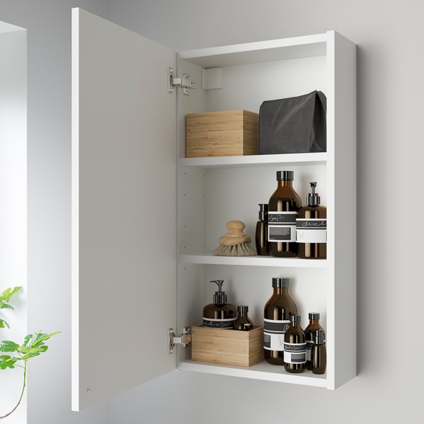 Witte wandkast met 3 planken met items die worden weergegeven. Stevig gemonteerd met zichtbare scharnieren.