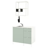 Modern groen keukenblok met gootsteen, planken en witte achtergrond.