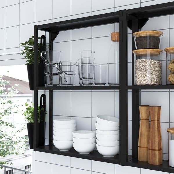Zwart metalen wandrek met glazen potten, schalen en planten.